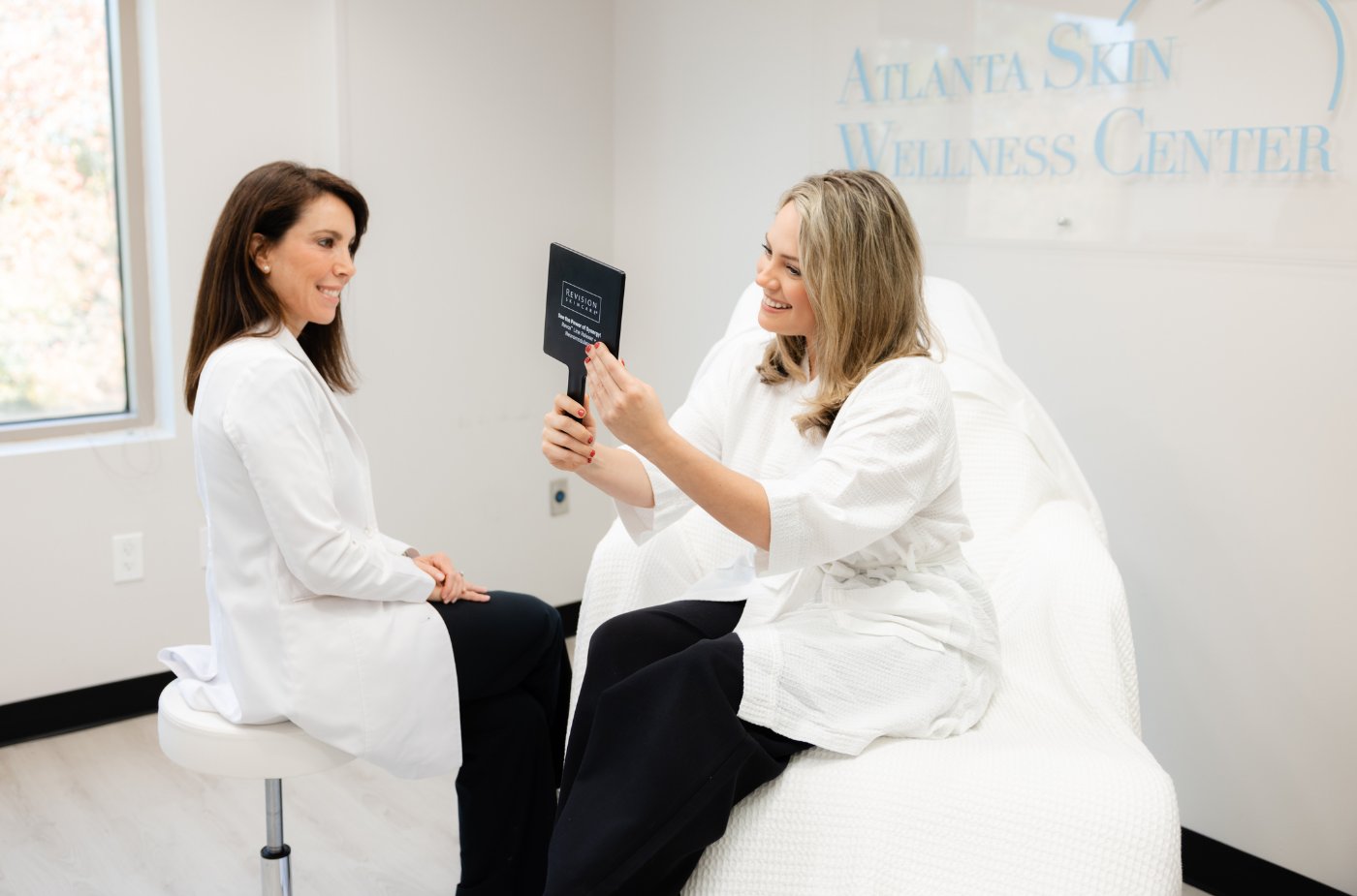 Dr. Elise Barnett consulting with a patient at Atlanta Skin Wellness Center, reviewing skincare recommendations in the treatment room